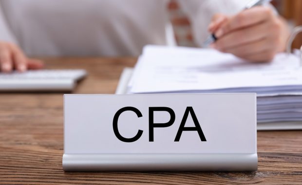 CPA name plate on the desk and a woman working on the backdrop