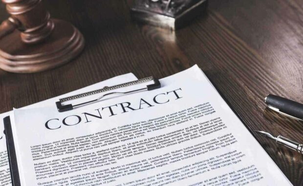 juridical contract on wooden table with pen and hammer, law concept