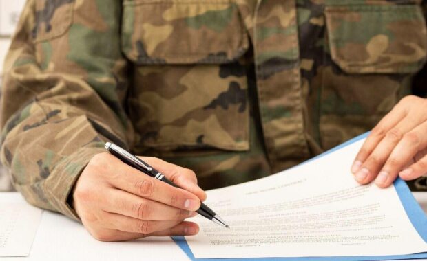 executive military man hands signing contract on a desk at work