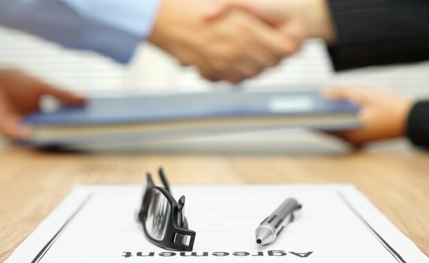 businessman and businesswoman are shaking hands and exchanging folder after agreement was reached