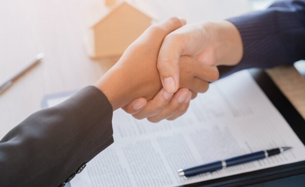 agent shake hands after customer signing contract