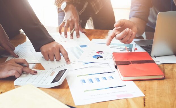 people meeting using laptop computer calculator notebook stock market chart paper