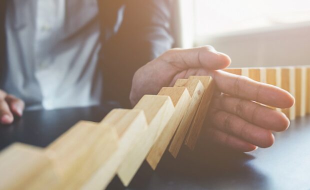 hand of business woman stopping falling blocks on table for concept about taking responsibility