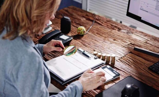 auditor hand checking invoice using magnifying grass