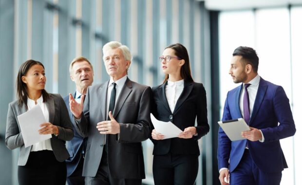 Group of political delegates in formalwear listening to their leader on their way to press conference